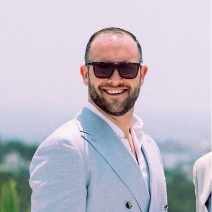 Man with shades on smiling at camera with suit on
